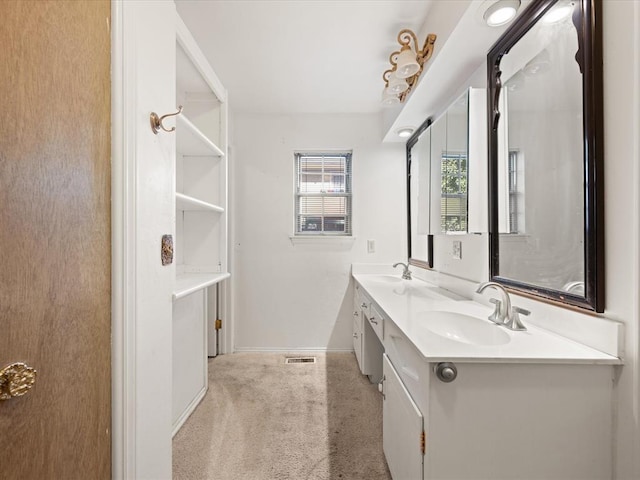 bathroom featuring double vanity, visible vents, baseboards, and a sink