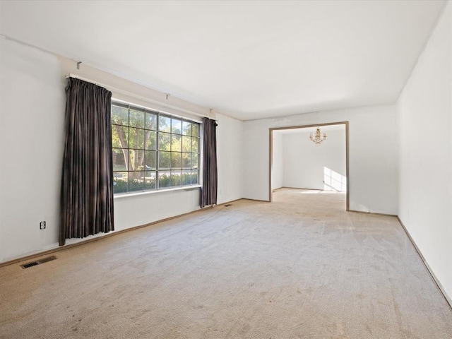 carpeted empty room with a notable chandelier and visible vents