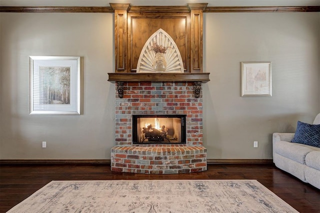 living room featuring a brick fireplace, baseboards, wood-type flooring, and ornamental molding