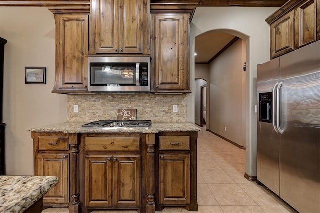 kitchen with decorative backsplash, arched walkways, appliances with stainless steel finishes, and ornamental molding