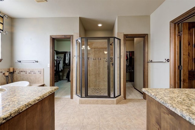 full bathroom featuring tile patterned floors, a stall shower, vanity, and a walk in closet