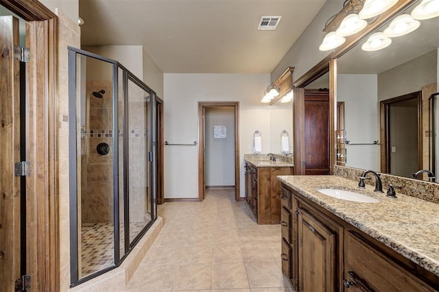 full bath featuring visible vents, a stall shower, two vanities, and a sink