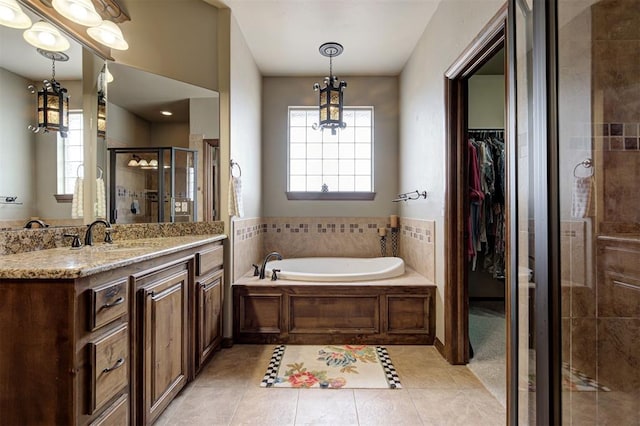 full bathroom with a shower stall, a walk in closet, tile patterned floors, a notable chandelier, and vanity