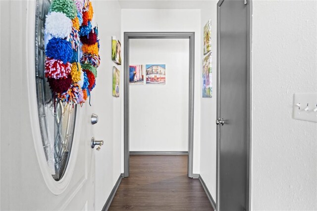 hall featuring dark wood-type flooring and baseboards