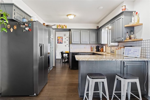 kitchen featuring stainless steel fridge, a peninsula, gray cabinetry, and a sink