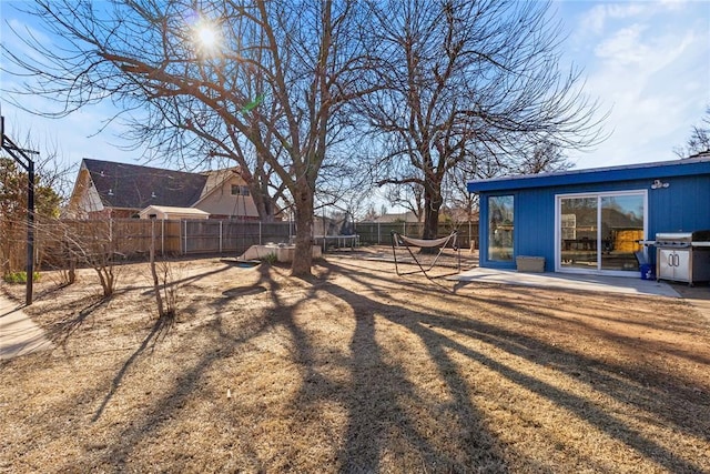 view of yard with a patio, a trampoline, and fence