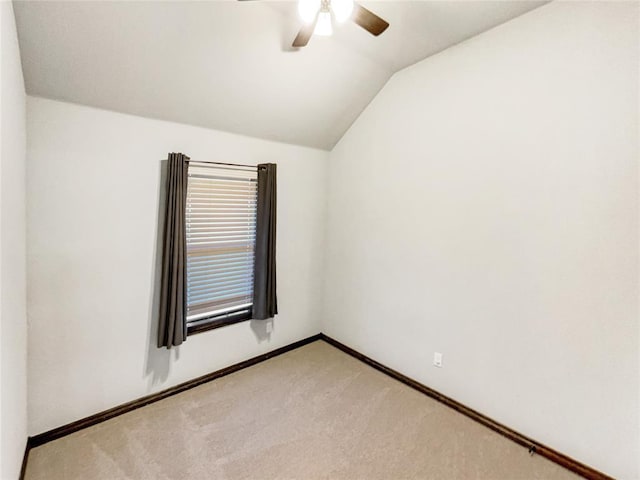 empty room featuring a ceiling fan, vaulted ceiling, light colored carpet, and baseboards