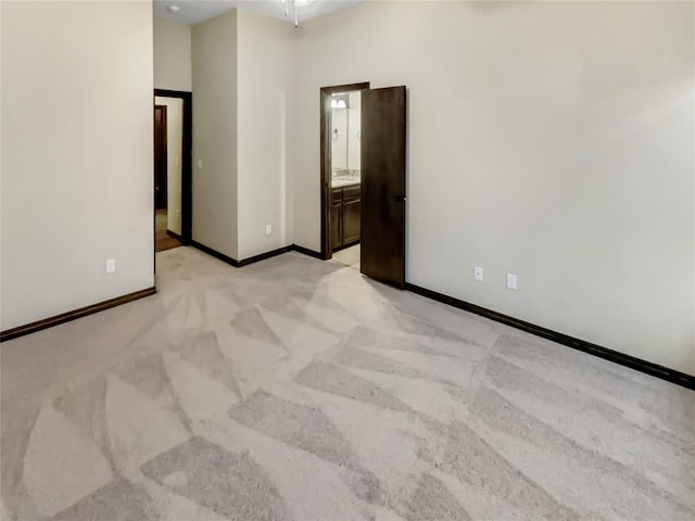 empty room featuring light carpet and baseboards