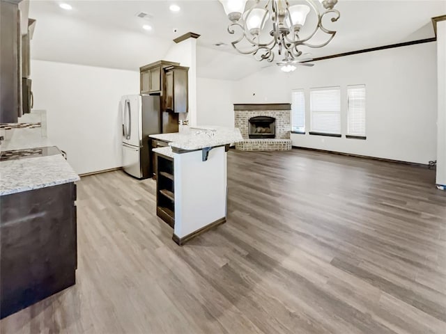 kitchen featuring visible vents, light wood-type flooring, lofted ceiling, a brick fireplace, and open floor plan