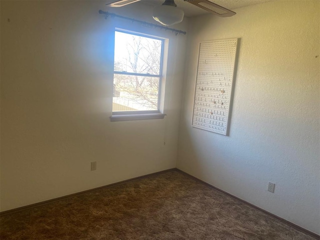 carpeted spare room featuring ceiling fan and baseboards