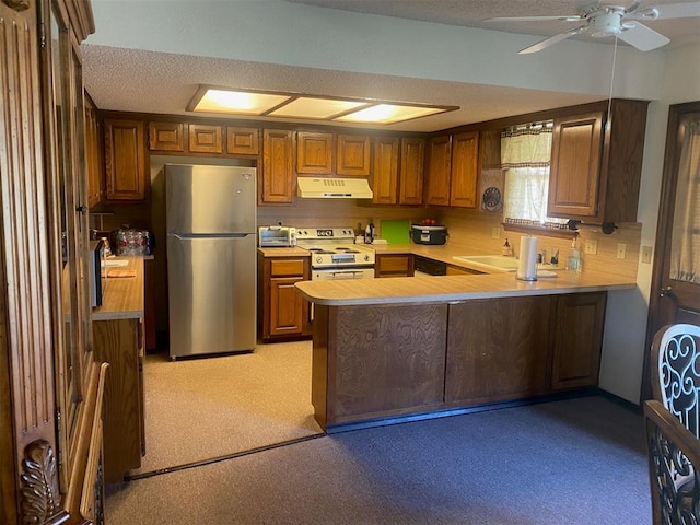 kitchen featuring under cabinet range hood, range with electric stovetop, freestanding refrigerator, a peninsula, and light countertops