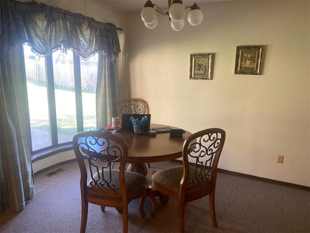 carpeted dining room featuring visible vents, baseboards, and an inviting chandelier