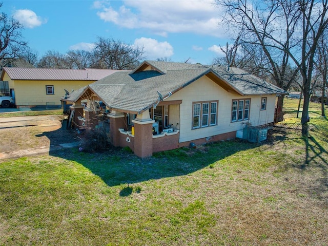 back of property featuring central AC, a lawn, and roof with shingles