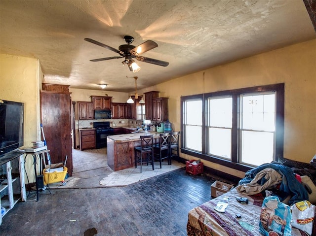 kitchen with black appliances, a breakfast bar, a ceiling fan, a textured ceiling, and a peninsula