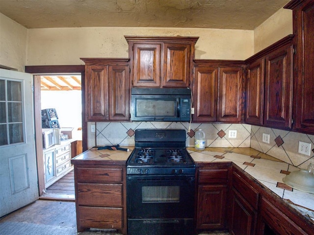 kitchen with backsplash, black appliances, and tile counters