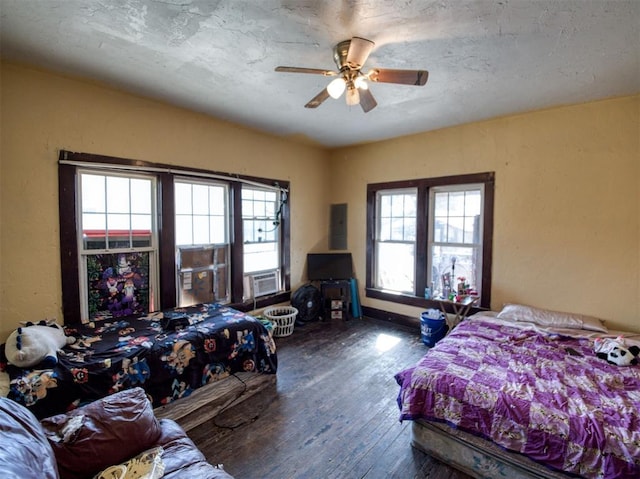 bedroom with ceiling fan, multiple windows, a textured ceiling, and wood-type flooring