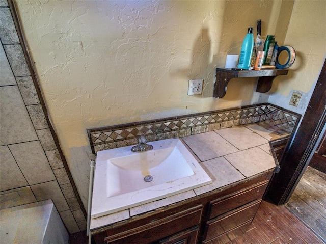 bathroom with wood finished floors, a textured wall, and a sink