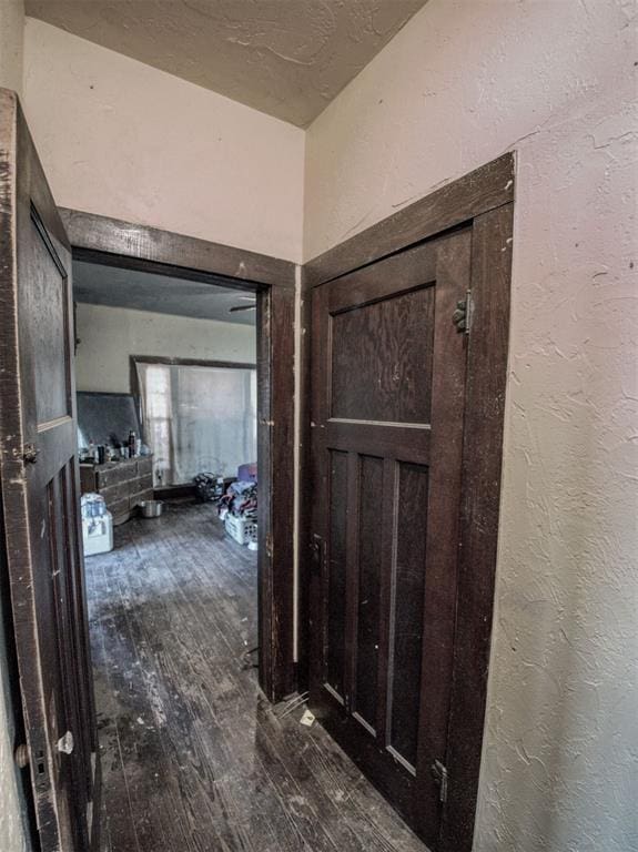 hallway with dark wood-style flooring and a textured wall