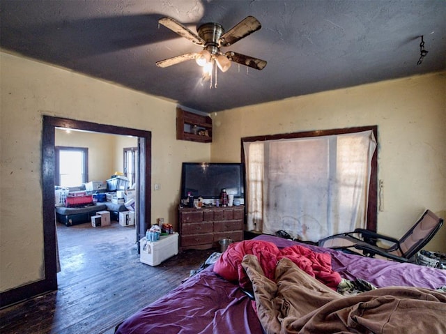 bedroom featuring ceiling fan, wood finished floors, and a textured ceiling