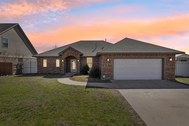 view of front facade featuring a front lawn, fence, roof with shingles, a garage, and brick siding