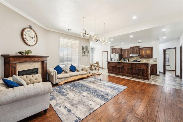 living room featuring visible vents, baseboards, ornamental molding, an inviting chandelier, and dark wood-style floors