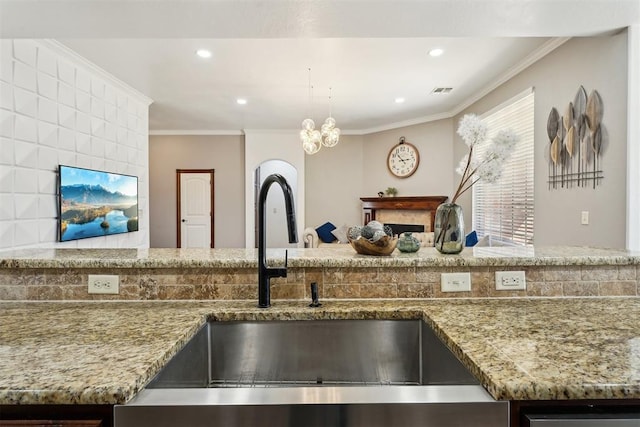 kitchen with light stone counters, recessed lighting, ornamental molding, and a sink