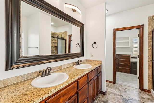 bathroom featuring double vanity, baseboards, a stall shower, and a sink