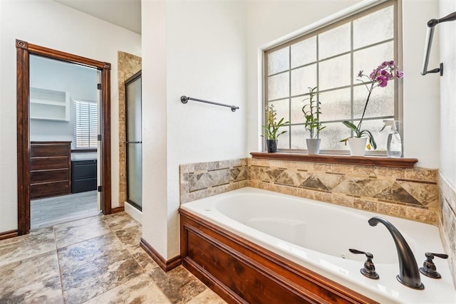 bathroom featuring a shower stall, a garden tub, and baseboards