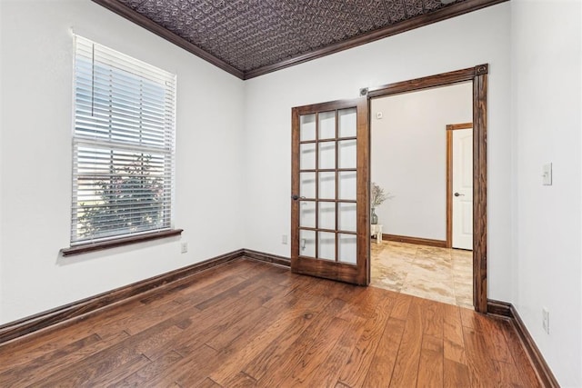 spare room with baseboards, ornamental molding, french doors, an ornate ceiling, and wood-type flooring