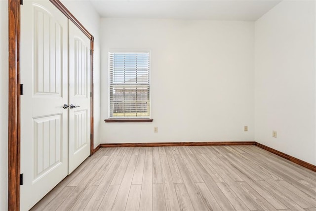 unfurnished bedroom with light wood-type flooring, baseboards, and a closet