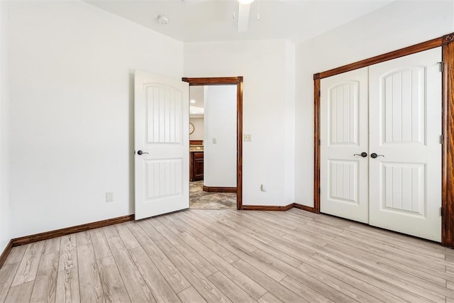 unfurnished bedroom with baseboards, a closet, and light wood finished floors