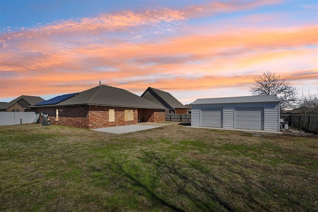 back of house featuring a patio, a fenced backyard, a yard, an outdoor structure, and a garage