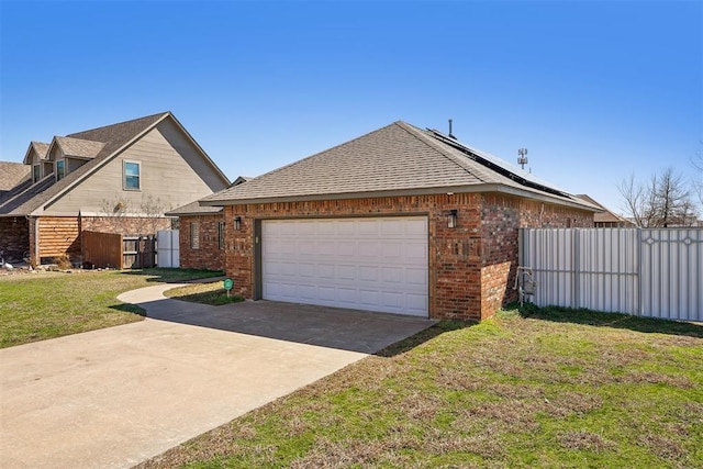 view of side of home featuring driveway, roof mounted solar panels, fence, a yard, and brick siding