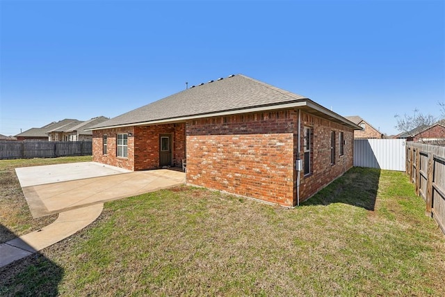 rear view of house with a patio, a yard, a fenced backyard, and brick siding