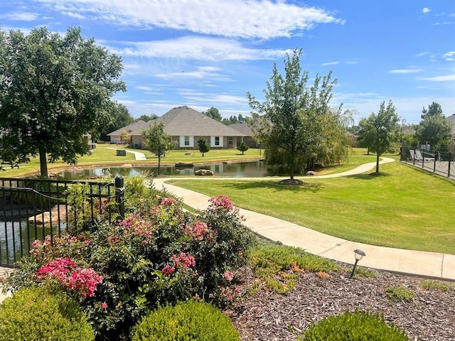 view of community featuring a yard, fence, and a water view