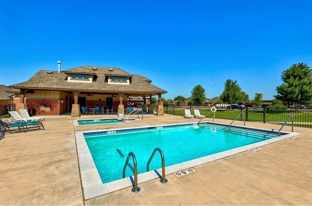 pool featuring fence, a community hot tub, and a patio area