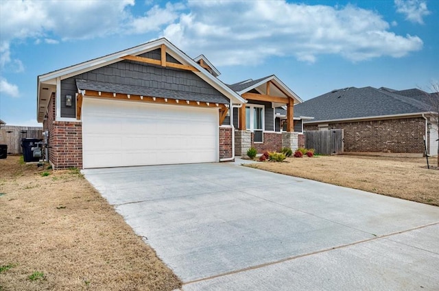 craftsman inspired home with brick siding, concrete driveway, a garage, and fence