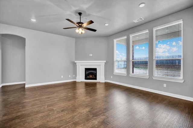 unfurnished living room with dark wood-type flooring, baseboards, visible vents, and ceiling fan