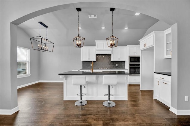 kitchen with visible vents, lofted ceiling, built in microwave, oven, and dark countertops