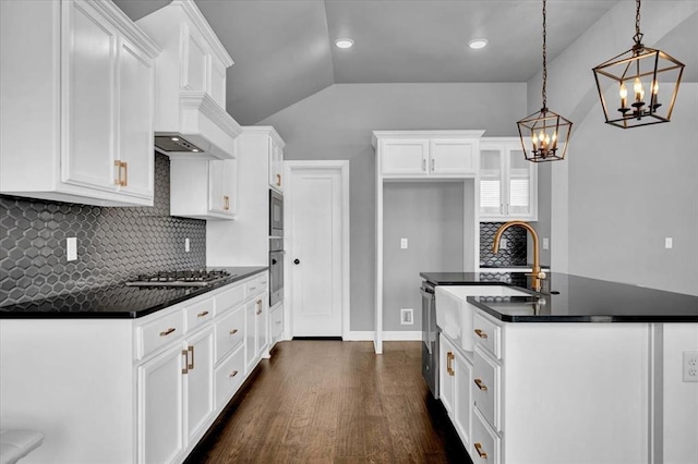 kitchen featuring a kitchen island with sink, dark countertops, dark wood-style floors, white cabinetry, and stainless steel appliances