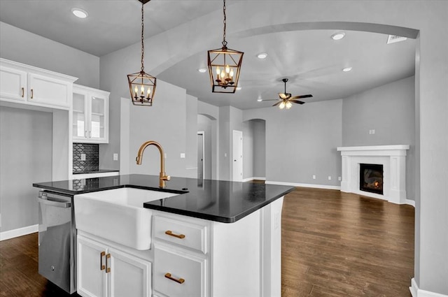 kitchen with a sink, backsplash, dark wood-style floors, arched walkways, and dishwasher