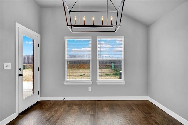 unfurnished dining area featuring a healthy amount of sunlight, a chandelier, and dark wood-style flooring