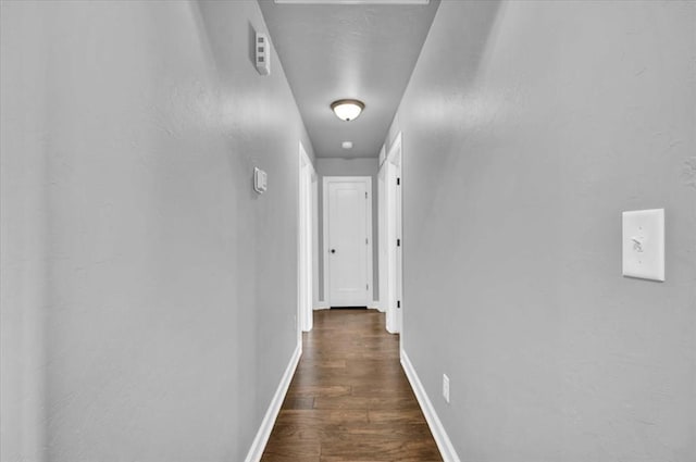 corridor with baseboards and dark wood-type flooring