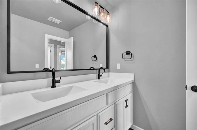 full bathroom with double vanity, baseboards, visible vents, and a sink