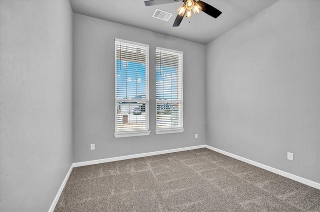 unfurnished room featuring baseboards, visible vents, dark carpet, and ceiling fan