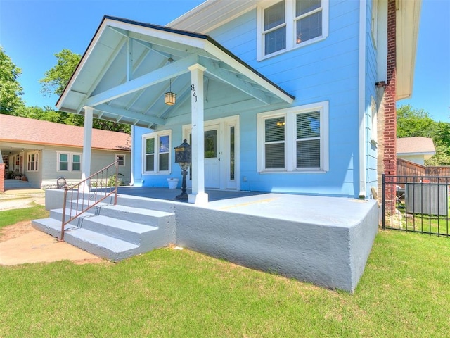 view of front of property with covered porch, a front lawn, and fence