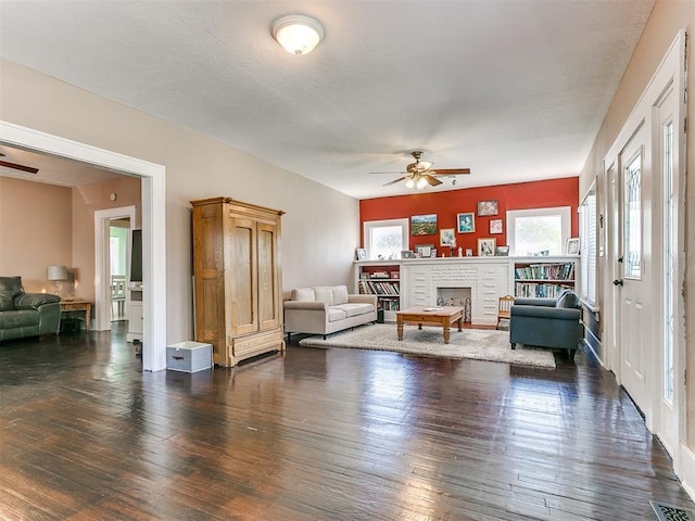 living area featuring hardwood / wood-style floors, a brick fireplace, visible vents, and ceiling fan