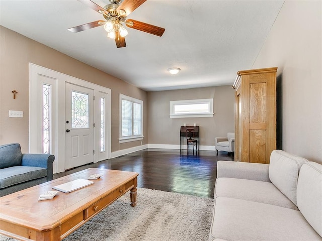 living room with baseboards, dark wood-type flooring, and ceiling fan