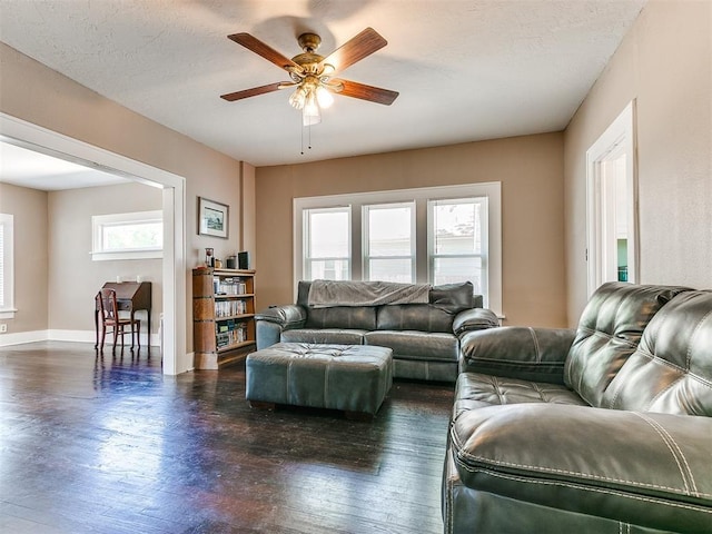 living area with dark wood finished floors, a ceiling fan, baseboards, and a textured ceiling