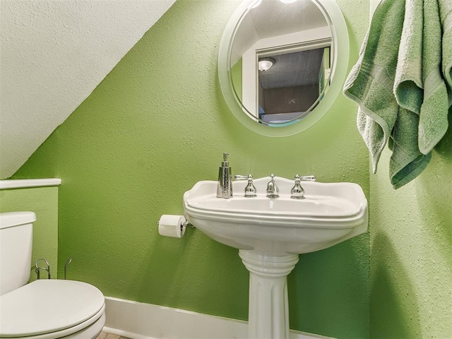 half bath with toilet and a textured wall